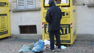 Un povero cerca degli indumenti in un container della Caritas