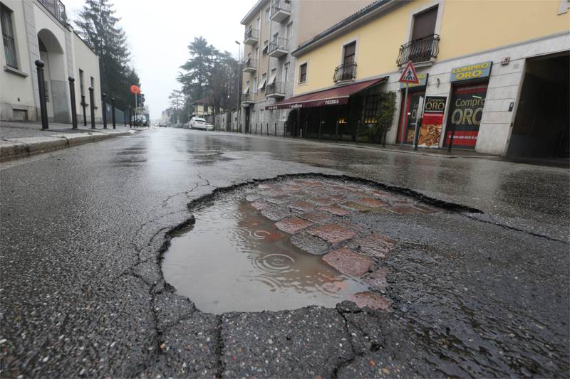 Una buca nell’asfalto in via Lecco. Sotto s’intravede la vecchia pavimentazione in porfido