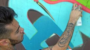 Il rapper Emis Killa impegnato a graffitare con un gruppo di writers i giardini comunali di via Brianza