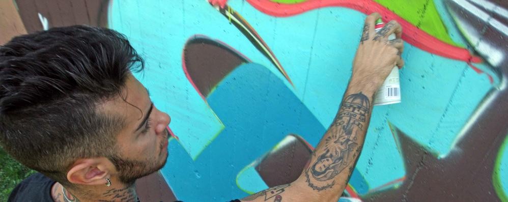 Il rapper Emis Killa impegnato a graffitare con un gruppo di writers i giardini comunali di via Brianza