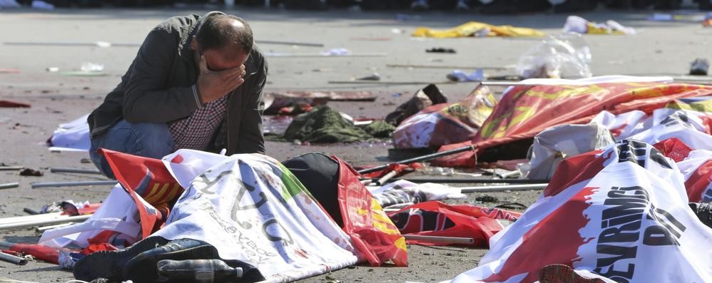 Un uomo piange davanti ai cadaveri dei manifestanti uccisi dai kamikaze in Turchia