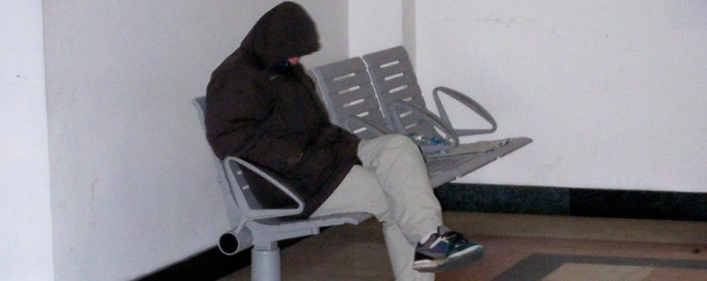 Un uomo dorme di primo mattino nella sala d'attesa della stazione di Seregno