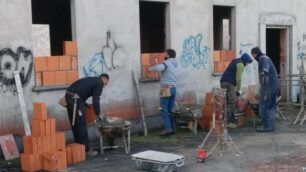 Operai al lavoro per murare le finestre della cascina