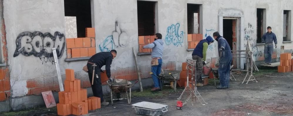 Operai al lavoro per murare le finestre della cascina