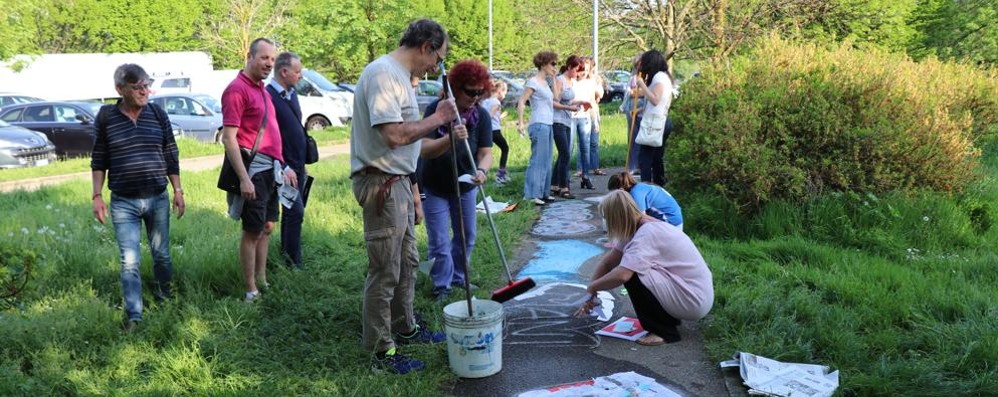 Genitori volontari che ricoprono le scritte diffamatorie sulla strada con disegni di carta