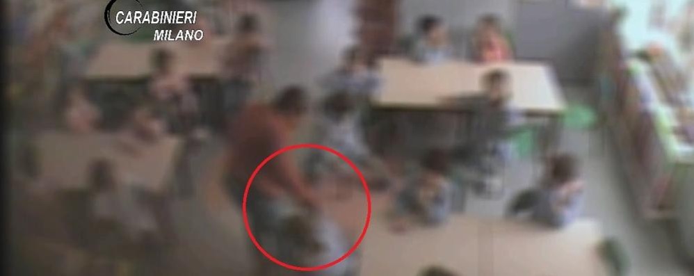 Un fermo immagine del filmato diffuso dai  carabinieri: nel cerchio si nota la mano della maestra afferrare i capelli di una bambina