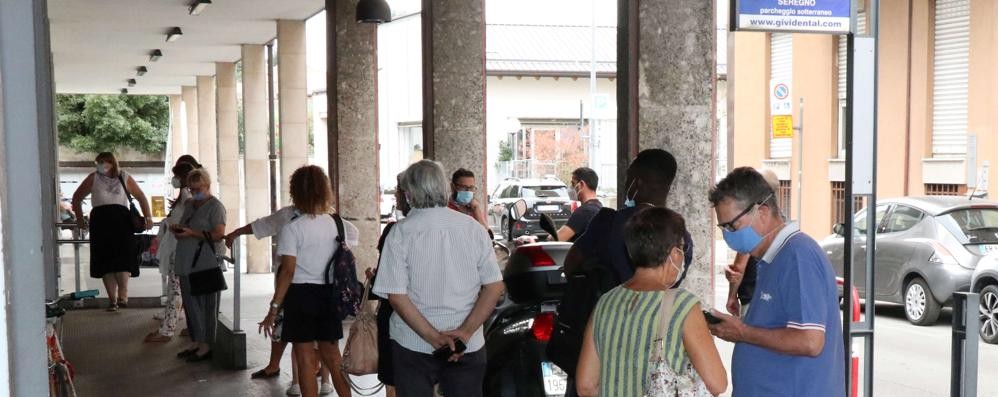 Le file sotto il colonnato di via Medici per accedere all'ufficio postale ( foto Volonterio)