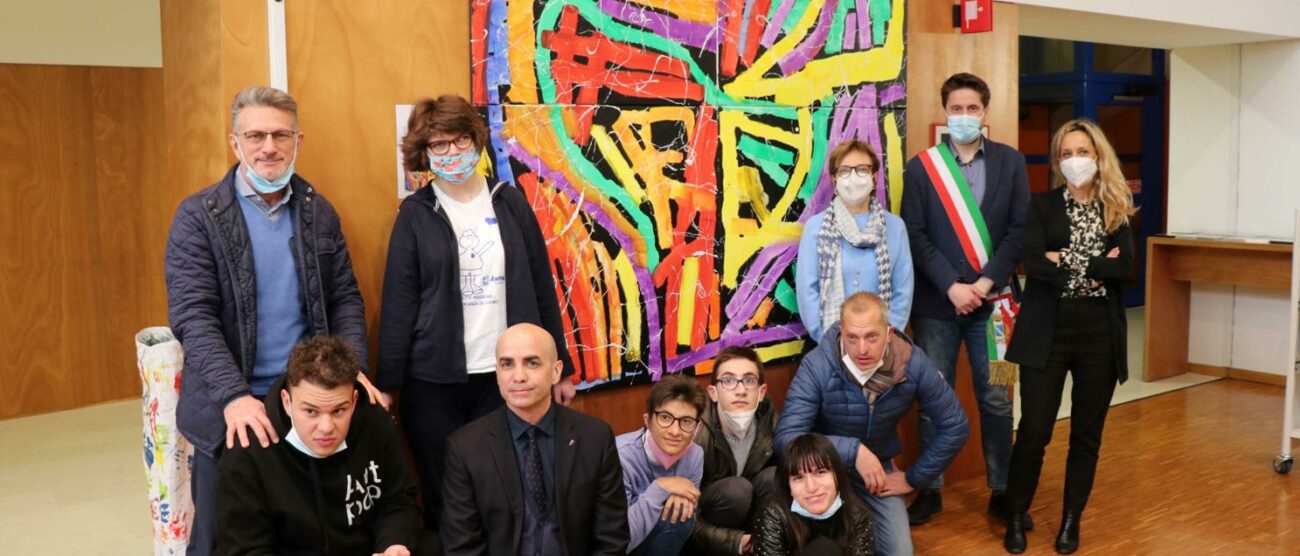 Un gruppo di ragazzi autistici delle associazioni Anffas e FacciaVista di Seregno davanti ad una delle loro opere presenti nella civica biblioteca di Seregno